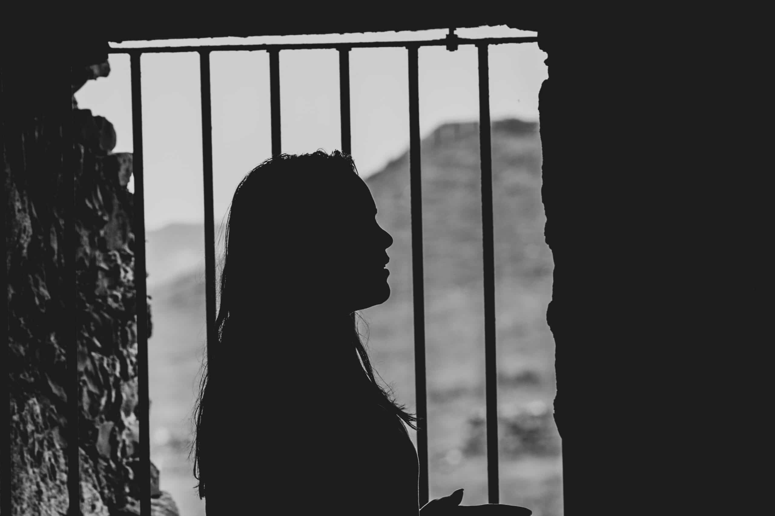 Silhouette Frau vor Gittertür Gefängnis dunkel