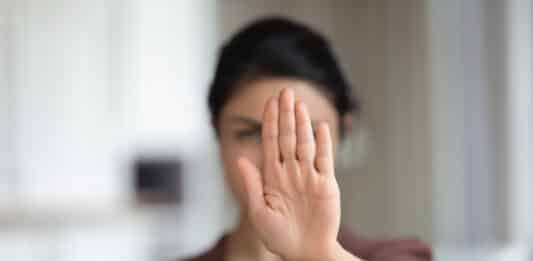 Eine Frau hebt abwehrend ihre Hand.