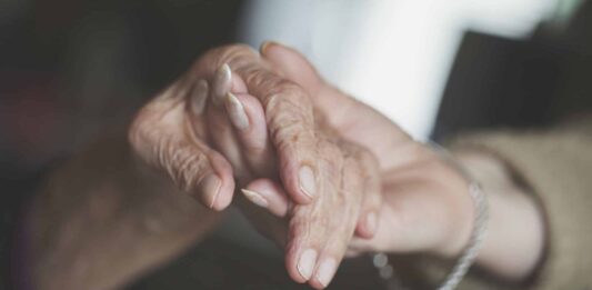 Junge Frau hält Hand einer Seniorin Alter krank