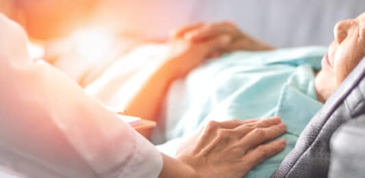 Krankenschwester berührt die Schulter einer Patientin