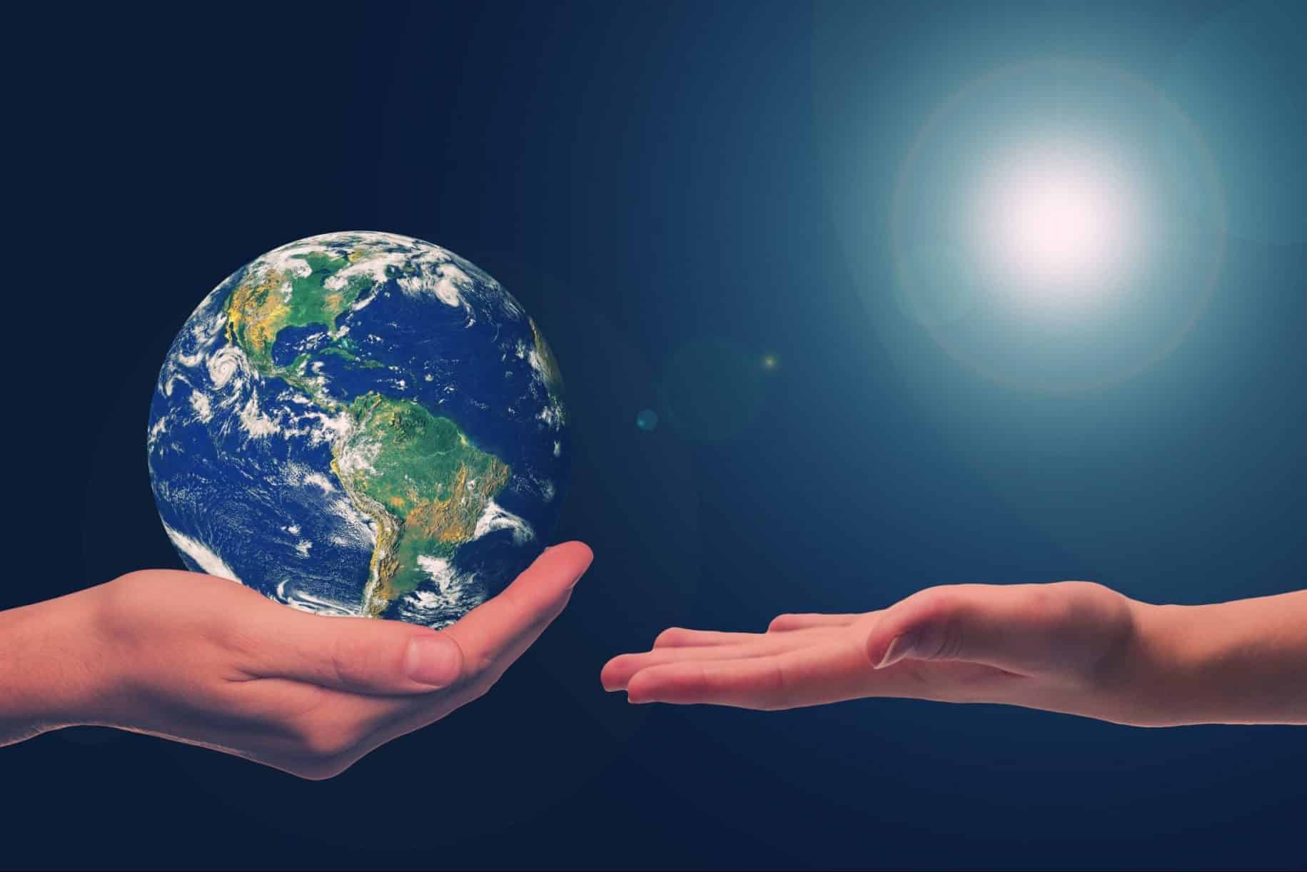 Eine Hand überreicht einer anderen eine Erde.