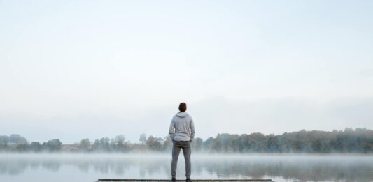 Mann steht alleine auf einem Steg am wasser