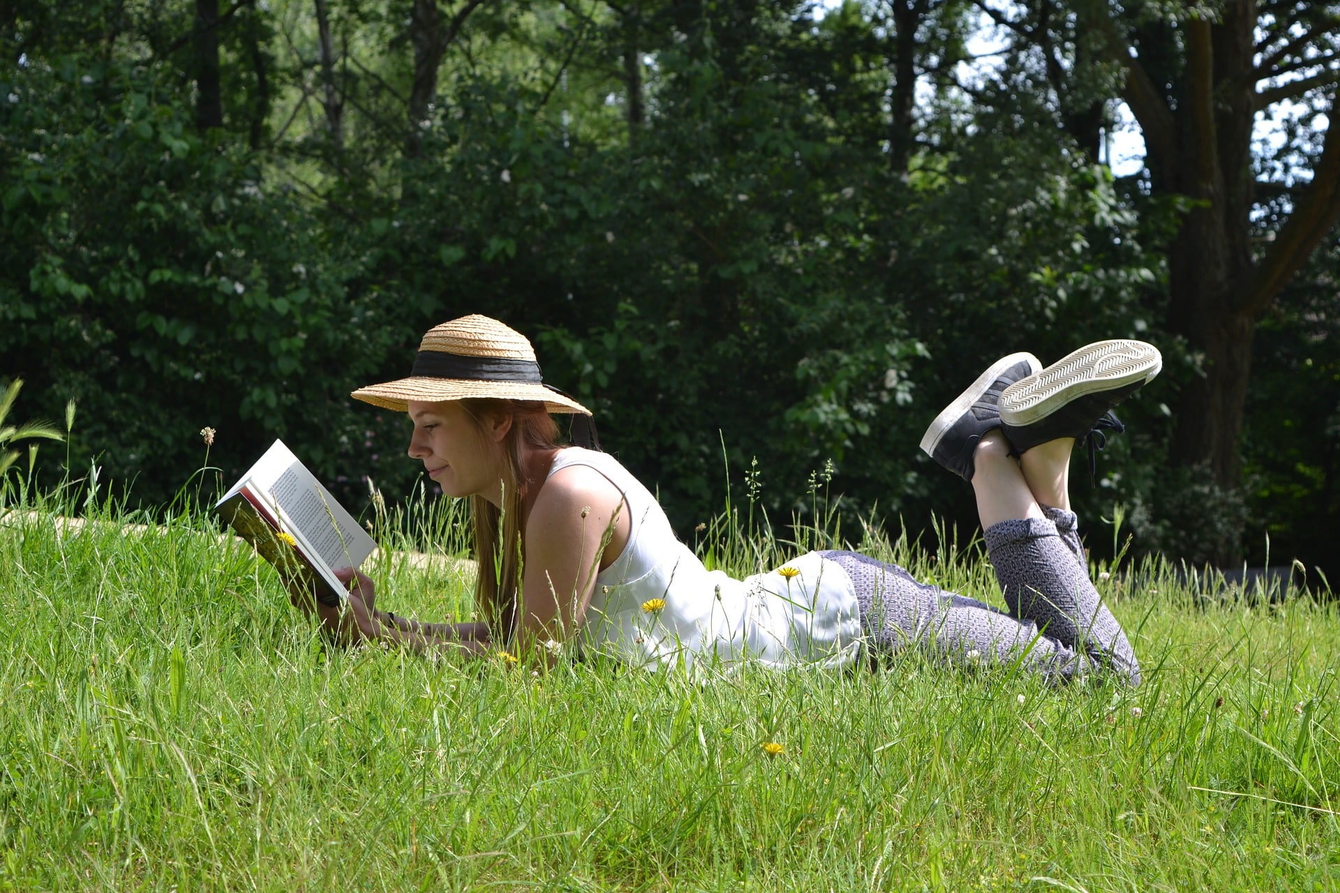 Frau liest Buch auf einer Wiese