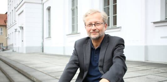 Professor Doktor Michael Herbst sitzt auf Treppenstufen