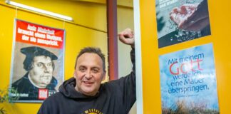 Mittagspause beim „Pommes-Jesus“ Imbissinhaber Michael Zielke steht neben einem evangelistischen Plakat.