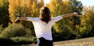 Evangelisation: Das ist das Gute an der Guten Nachricht Eine Frau steht mit ausgestreckten Armen auf einem Feld.