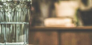 Das Glas ist nicht halb leer – aber auch nicht halb voll Ein halb volles Wasserglas steht auf einem Küchentisch.