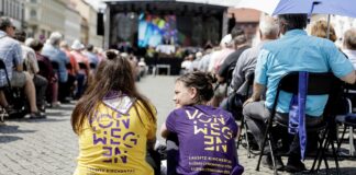 Mehr als 15.000 Besucher bei erstem Lausitz-Kirchentag Zwei Frauen sitzen auf einem Boden aus Pflastersteinen. Im Hintergrund Stuhlreihen voll mit Menschen und eine Bühne.