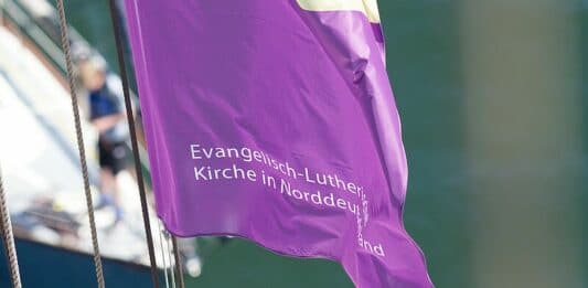 Eine Fahne der Nordkirche weht im Wind.
