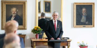 Hans-Joachim Eckstein mit Bundesverdienstkreuz ausgezeichnet Hans-Joachim Eckstein steht hinter einem Pult mit Mikrofon und hält eine Rede.