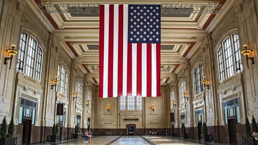 Eine riesige US-Flagge hängt von der Decke einer großen Eingangshalle.