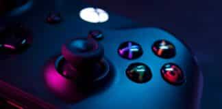 Zocken im Reliunterricht Ein schwarzer X-Box-Controller wird von einer rosa Lichtquelle angestrahlt.
