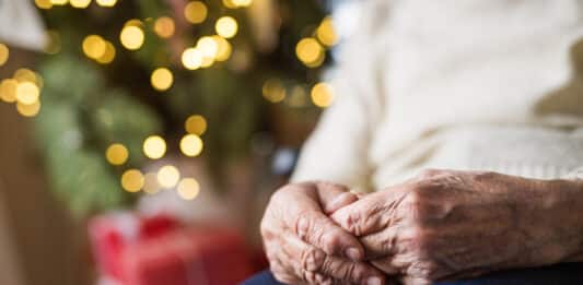 Seniorin sitzt alleine vor einem weihachtsbaum