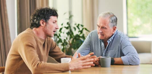 Ein junger und ein älterer Mann unterhalten sich an einem Tisch