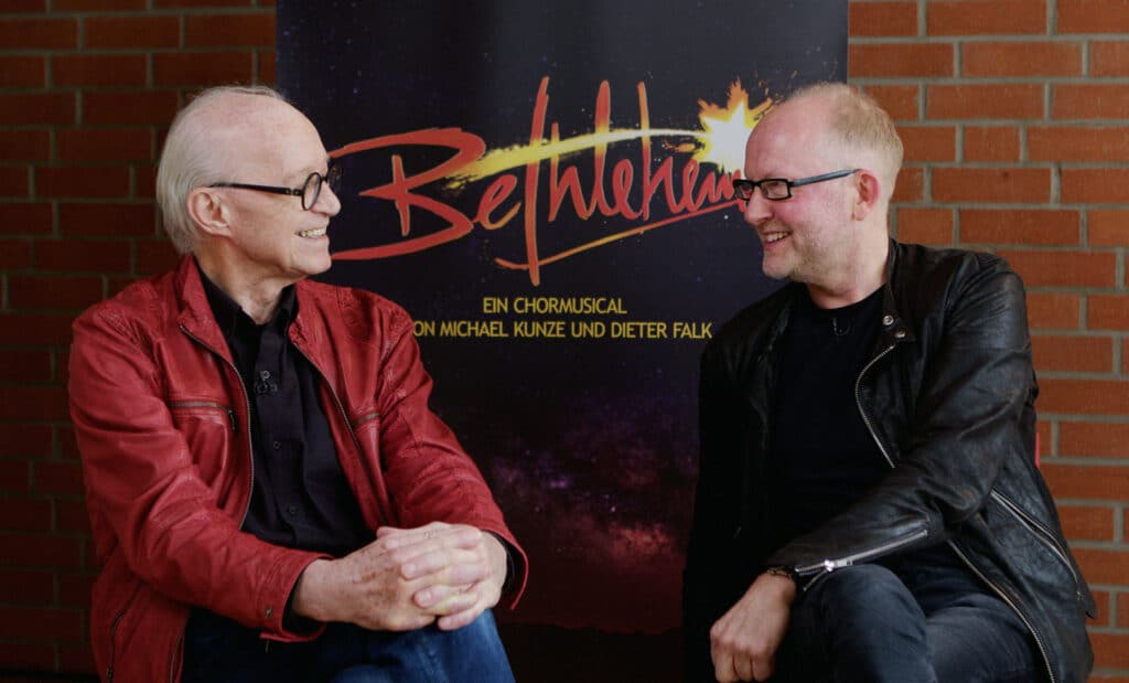 Michael Kunze (links) und Dieter Falk vor einem Plakat des Betlehem-Musicals Creative Kirche