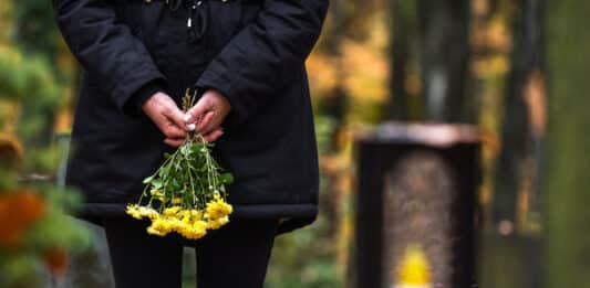 Frau mit Blumen an einem Grab Friedhof