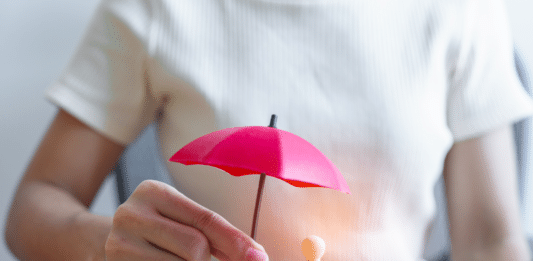 Person mit Mini-Regenschirm auf einem Tisch