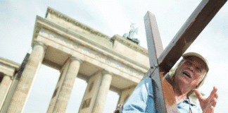 Weltrekord: Prediger Arthur Blessitt wanderte einmal um die Welt Mann mit einem Kreuz in der Hand steht vor dem Brandenburger Tor