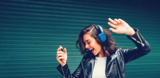 Junge Frau hört Musik und tanzt