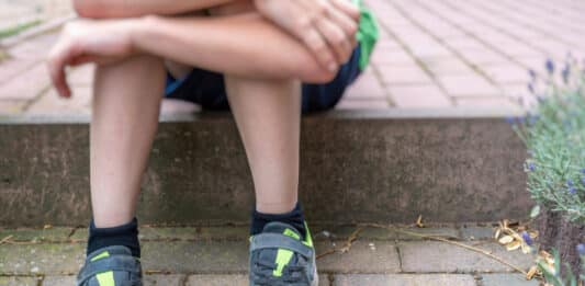 Junge mit kaputten Schuhen