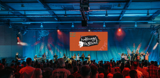Eine Halle, gefüllt mit Menschen beim Hoffnungsfestival, von hinten fotografiert.