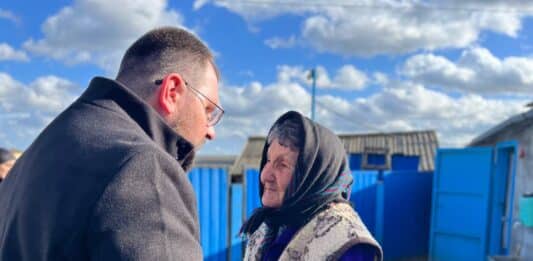 Ukrainischer Bischof Maksym Ryabukha im Gespräch mit einer alten Frau vor einem Gebäude