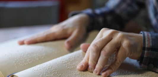 Blinde Frau liest ein Buch in Braille-Schrift