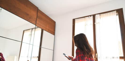 Frau mit Smartphone in der Hand in einem Zimmer
