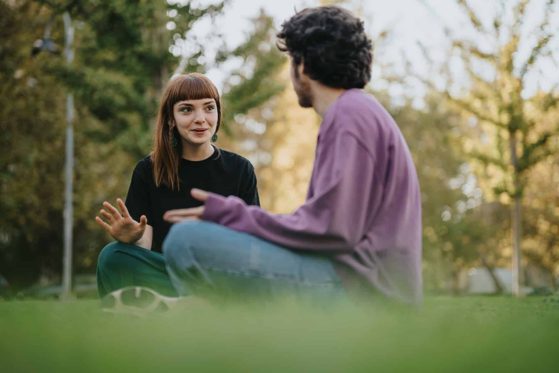 Ein Mann und eine Frau sitzen auf einer Wiese und reden.