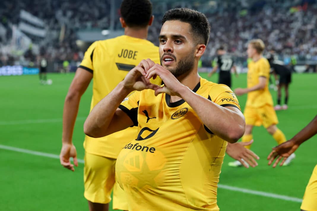 Fußballspieler Yan Couto hat einen Fußball unter seinem Trikot und zeigt mit den Händen ein Herz.