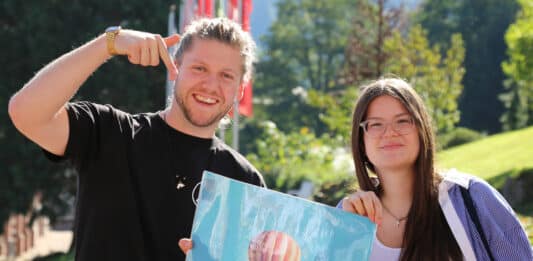 Ein junger Mann und eine junge Frau halten ein Plakat. Darauf steht "upfahrt Gebet & Mission".