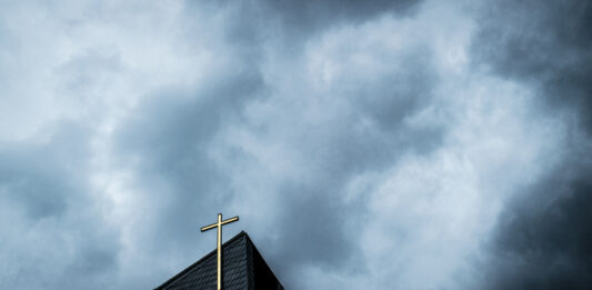 Kirchturm mit dunklen Wolken