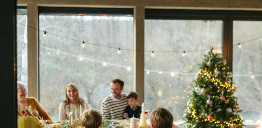 Eine Familie sitzt an einem Tisch und feiert Weihnachten.
