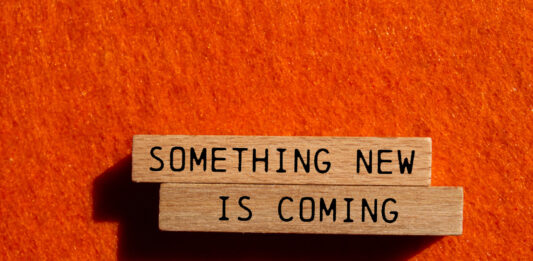 Something new is coming - Botschaft auf einem Holzblock neu