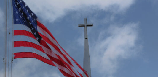 Flagge der USA weht vor einem Kirchturm
