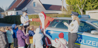 Sachsen-Anhalt: Polizei rettet Weihnachtsmann Ein Weihnachtsmann und zwei Polizistinnen stehen neben einem Polizeiauto und sprechen mit mehreren KIndergartenkindern.