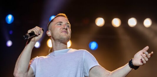 Mike Posner auf der Bühne, lächelnd