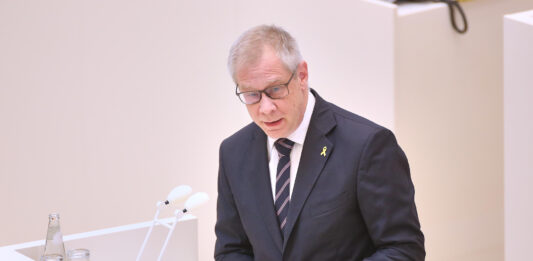 Brandenburgs Antisemitismusbeauftragter Andreas Büttner steht an einem Redepult.