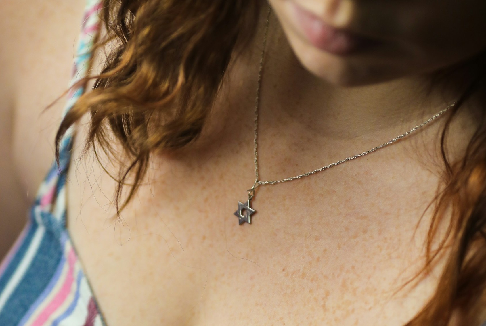 Eine Frau trägt eine Kette mit einem Davidstern um den Hals.