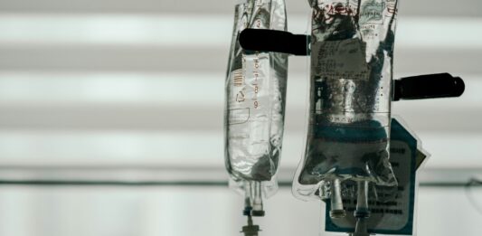 Eine Infusion hängt vor einem leicht verdunkelten Fenster