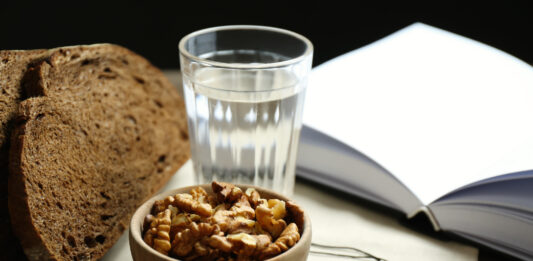 Brot, Wasser und eine Schale Walnüsse neben einem Kruzifix