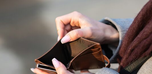 Eine Frau zeigt ihr leeres Portemonnaie