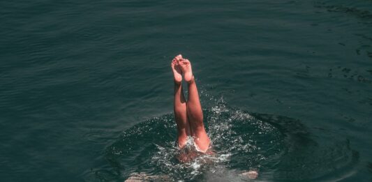 Eine Person springt ins Wasser und taucht ein.