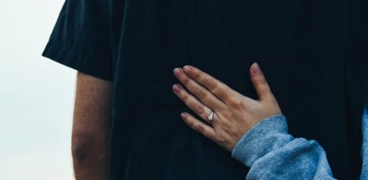 Eine Frau legt ihre Hand auf den Rücken eines Mannes.