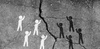 Studie: Viele Deutsche denken rassistisch Weiße und schwarze Strichmännchen streiten an eine Höhlenwand gemalt, ein Spalt ist zwischen ihnen.
