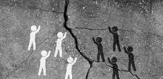 Weiße und schwarze Strichmännchen streiten an eine Höhlenwand gemalt, ein Spalt ist zwischen ihnen.
