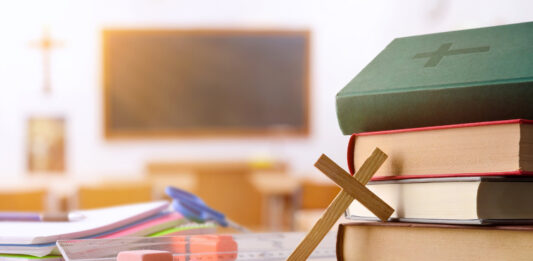 Klassenzimmer mit Büchern, Kreuz und Bibel