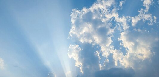 Die Sonne strahlt durch Wolken am Himmel.
