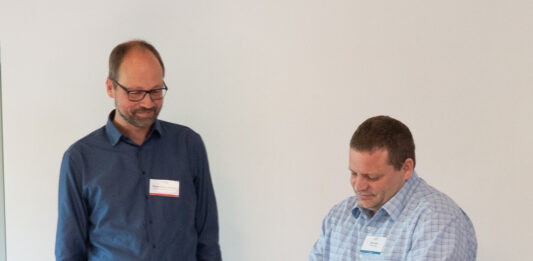 Martin Abraham (ReachAcross) und Simon Bohn (DMG) unterzeichnen die Kooperationsvereinbarung der Missionswerke ReachAcross und DMG.