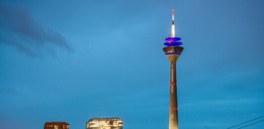 Der Rheinturm in Düsseldorf, erleuchtet bei Dämmerung